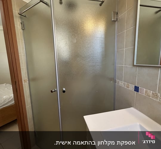 מקלחון זכוכית עם דלת מתכת ומראה על הקיר